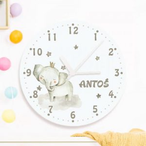 Szklany zegar ścienny z białym tłem i grafiką słonia w koronie. Imię dziecka wpisane na tarczy zegara.