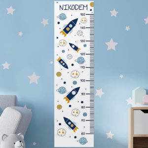 Kosmiczne Przygody w wersji miarki wzrostu dla najmłodszych. Białe tło zdobią rakiety przemierzające galaktykę pełną planet i gwiazd. W górnej części umieścimy imię dziecka.