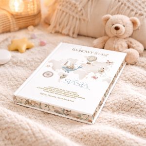 Książka zatytułowana 'Bajkowy Świat', leżąca na miękkim kocyku, obok puszystego misia i ozdobnych elementów, takich jak gwiazdka i kolorowe kamyki. Na okładce widoczna mapa świata oraz ilustracje balonów i zwierząt.