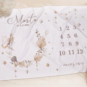 Kocyk z imieniem "Marta", datą urodzenia 6.11.2024, liczbami od 1 do 12 oraz delikatnymi rysunkami roślinnymi i zwierzęcymi.