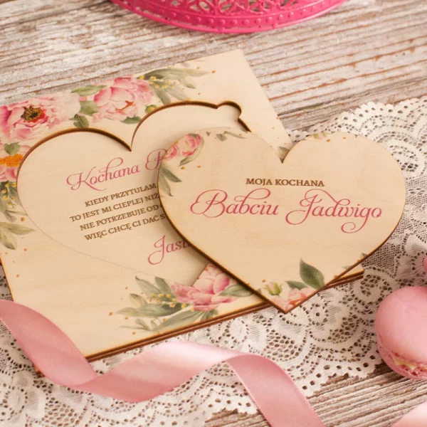 Personalizowana, drewniana laurka z życzeniami dla babci w kształcie serca i grafiką różowych kwiatów