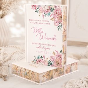 Biblia Weroniki z ozdobnym różowym motywem kwiatowym, dedykacja na pamiątkę komunii świętej, umieszczona na eleganckim tle.