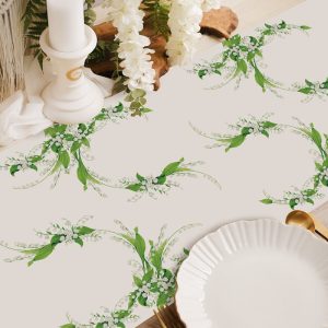 Dekoracja stołu w postaci obrusu na Komunię. Bieżnik z zielonymi listkami i białymi kwiatkami konwalii.
