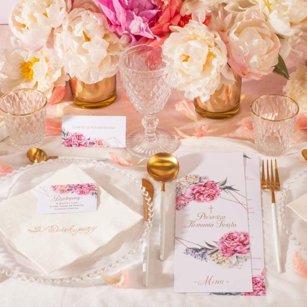 Dekoracje na komunijny stół z kolekcji Sweet Peony. Dodatki wzbogacone są o różowy motyw z grafiką kwiatów piwonii.