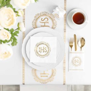 Białe serwetki stołowe ze złotym emblematem IHS.