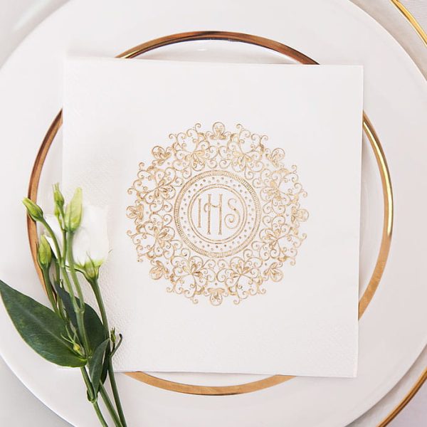 Komunijne serwetki ozdobne w kolorze białym. Na środku grafika złotej hostii zdobionej ażurowym wzorem dookoła. Elegancka dekoracja talerza na stole komunijnym.