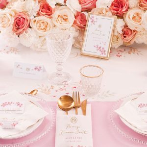 Aranżacja dekoracji stołu na Komunię Świętą w motywie różowych kwiatów magnolii