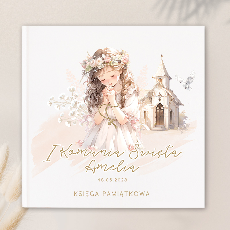Ilustracja przedstawiająca dziewczynkę w białej sukni, z delikatnymi różami we włosach i modlącej się z złożonymi dłońmi. W tle widoczny kościółek i gołąb. Na okładce tekst: 'I Komunia Święta Amelia 18.05.2028 Księga Pamiątkowa'.