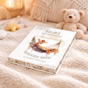 Książka w białej oprawie na tle jasnej, teksturowanej narzuty, z napisem "Bajki na dobranoc Karolinki Słodkich snów" oraz ilustracją żyrafy w hamaku, obok leży pluszowy miś.