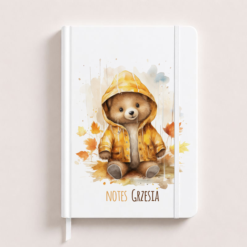 Notes z ilustracją pluszowego misia w żółtej kurtce, siedzącego pośród liści, z napisem "NOTES GRZESIA".