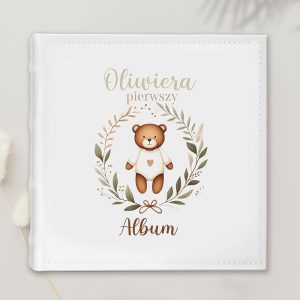 Biały album z ilustracją misia w ubranku z serduszkiem, otoczonym gałązkami i napisem 'Oliwiera pierwszy Album' w kolorach beżowym i zielonym.