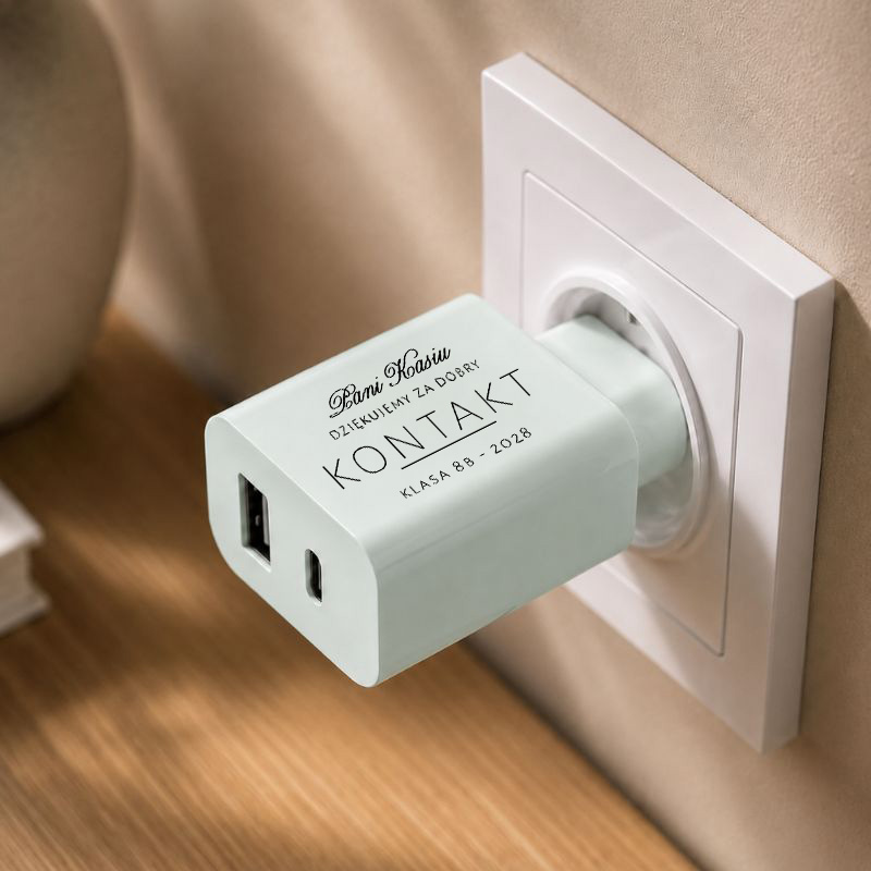 Zielony adapter z portami USB, podłączony do gniazdka, z napisem "Kontakt" oraz informacjami o szkole i klasie.