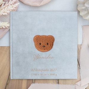 Szary album na zdjęcia z haftowanym wzorem głowy niedźwiadka na okładce, z imieniem 'Stanisław', datą 22 listopada 2027, godziną 11:45 oraz informacjami o wadze i długości dziecka.