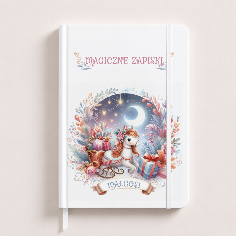 Notatnik z ilustracją różowego jednorożca w saniach, otoczonego kolorowymi prezentami i roślinami, z napisem "MAGICZNE ZAPISKI".