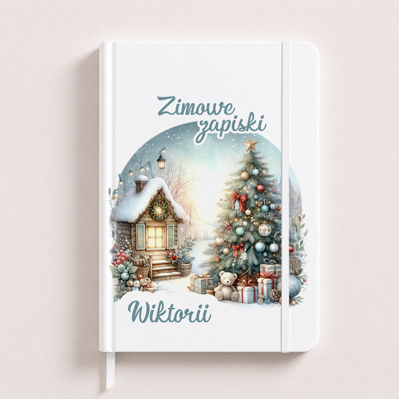 Biały notes z zimowym motywem, przedstawiający chatkę z oświetloną choinką i prezentami. Napis "Zimowe zapiski Wiktorii".