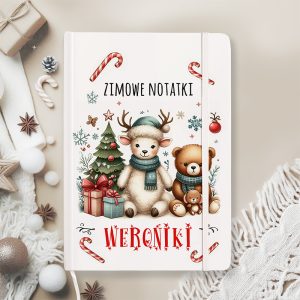 Notatnik z zimowym motywem renifera i misia na tle choinki i prezentów.