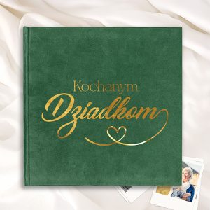 Zielona okładka albumu z napisem 'Kochanym Dziadkom' wykonanym w złotym kolorze, leżąca na jasnym tle z delikatnymi fałdami materiału.