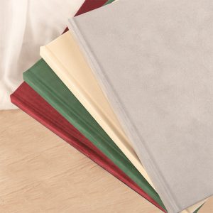 Widok na cztery kolorowe teczki w odcieniach szarości, zieleni, kremu i czerwieni ułożone na ciepłym drewnianym blacie, z białym tłem w górnej części obrazu.