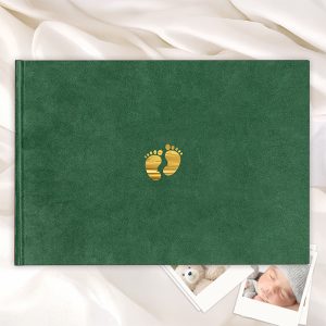 Zielona okładka albumu z wytłoczonymi, złotymi śladami stóp na środku, leżącego na białym tle z delikatnym materiałem i zdjęciami w kształcie kwadratu w tle.