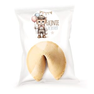 Ciasteczko z wróżbą w kształcie litery V, umieszczone w przezroczystym opakowaniu z etykietą przedstawiającą urocze kota trzymającego balony. Na etykiecie napis 'FAJNIE ŻE JESTEŚ!' w kolorze brązowym.