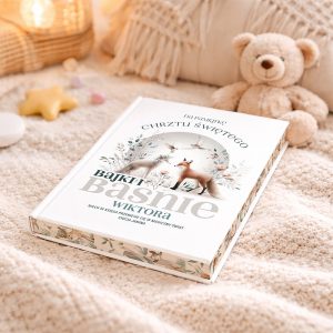 bajki-i-basnie-prezent-na-chrzest Otwarta książka na beżowym kocyku, z tytułem 'Bajki i Baśnie Wiktora' oraz ilustracjami lisów i kwiatów; w tle pluszowy miś i zabawki w kształcie gwiazdy i kulek.