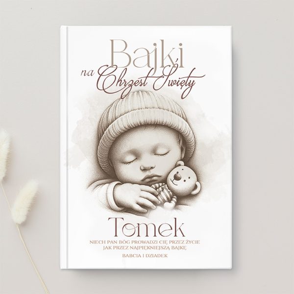Okładka książki z tytułem 'Bajki na Chrzest Święty', przedstawiająca śpiącego niemowlaka w wełnianym czapeczce, trzymającego pluszowego misia, z napisem 'Tomek' oraz dedykacją od babci i dziadka.