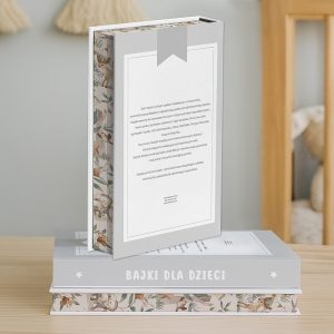 Książki leżą na drewnianej powierzchni, widoczna okładka z tytułem 'Bajki dla dzieci' oraz ilustracje zwierząt na bokach, w tle miękki, rozmyty kącik wypełniony zabawkami dziecięcymi.