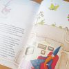 Ilustracja z kolorowanej książki dla dzieci przedstawiająca czarownicę unoszącą się w powietrzu, motyla, żabę i zielone rośliny, w tle widoczna postać mężczyzny w niebieskiej pelerynie siedzącego na czerwonym fotelu, otoczonego rysunkami na ścianie.