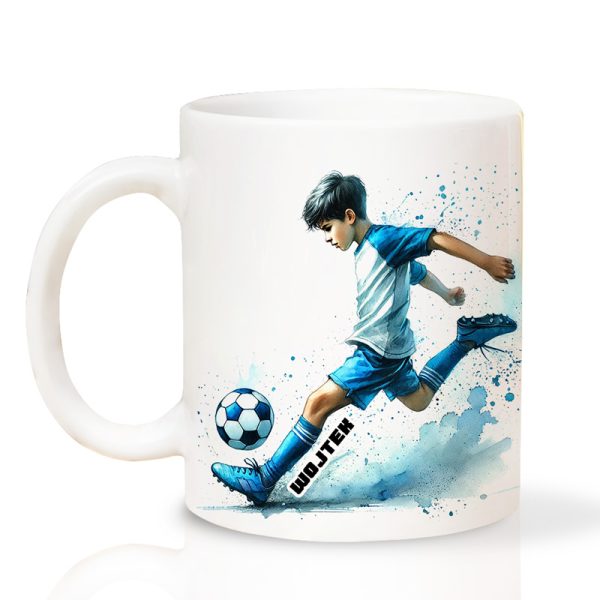 Ceramiczny kubek z ilustracją młodego chłopca w sportowym stroju, który kopie niebieską piłkę nożną, z efektownymi plamami farby w tle oraz imieniem "Wojtek" napisanym na kubku. KUBEK Dla Piłkarza Z Imieniem.