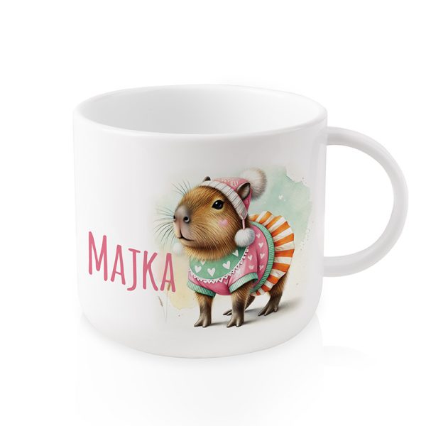 Kubek z ilustracją kapibary w kolorowej odzieży, noszącej różową czapkę i sukienkę, z napisem 'MAJKA' obok niej.