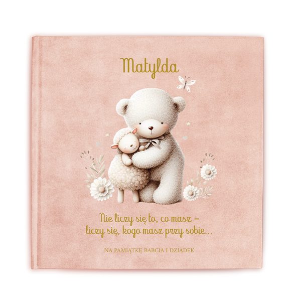 Okładka książki z tytułem "Matylda". Na okładce znajduje się ilustracja pluszowego niedźwiadka przytulającego owieczkę, z delikatnym tłem w kolorze różowym i kwiatowymi detalami. Na dole umieszczony jest tekst brzmiący: "Nie liczy się to, co masz - liczy się, kogo masz przy sobie... Na pamiątkę Babcia i Dziadek".