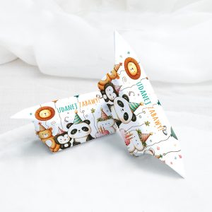 Dwa trójkątne pudełka ozdobne z wesołymi ilustracjami zwierząt, takich jak panda, lew i pingwiny, noszących kolorowe czapki urodzinowe, z napisem 'UDANET ZABAWY!' na tle jasnego materiału.