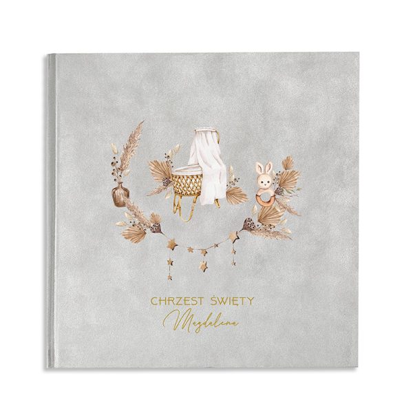 Szary album zdobiony delikatnymi ilustracjami, w tym koszykiem z białą pościelą, króliczkiem i gałązkami, z napisem 'CHRZEST ŚWIETY Magdalena' w złotym kolorze.