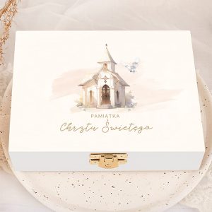 Biała skrzynka z ilustracją kościoła i napisem 'PAMIĄTKA Chrztu Świętego' w eleganckim, złotym kolorze, na delikatnym tle w odcieniach różu oraz małą gołębią.