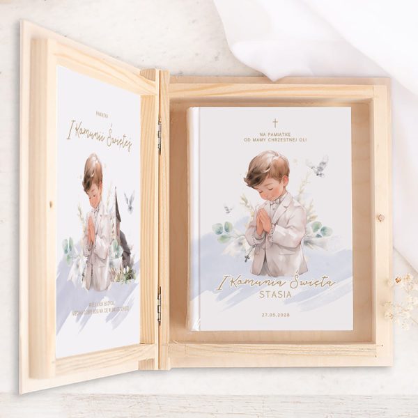 Pudełko z Biblią pamiątka komunii chłopca. Elegancka drewniana szkatułka, wewnątrz znajduje się książka z okładką przedstawiającą chłopca w białym stroju modlitewnym, składającego dłonie do modlitwy, otoczony delikatnymi rysunkami roślin oraz gołębiami. Na okładce napis 'I Komunia Święta Stasia', personalizowane imię i data 27.05.2028.