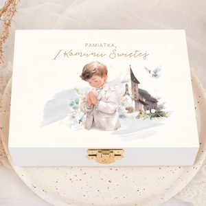Skrzyneczka na komunijne pieniądze chłopca. Biała skrzynka z ilustracją chłopca w białym garniturze modlącego się ze złożonymi dłońmi, obok obrazek kościoła i gołębia, z napisem 'Pamiątka, I Komunii Świętej' u góry.