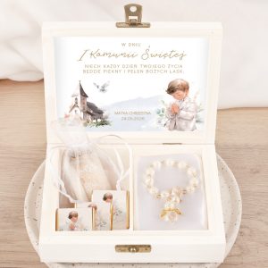 Skrzyneczka na komunijne pieniądze chłopca. Drewniana skrzynka z zawartością na pierwszą komunię, z ilustracją chłopca modlącego się oraz widokiem kościoła. Wewnątrz znajduje się różaniec, czekoladki oraz kartka z dedykacją. Data i nazwisko są również widoczne.