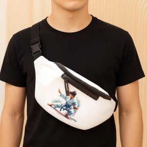 Mężczyzna noszący czarną koszulkę, z białą torbą na biodra z ilustracją chłopca w karate, w niebieskim kimonie, na tle jasnej, minimalistycznej przestrzeni.