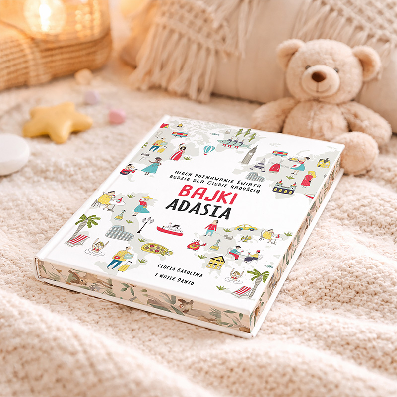 Książka 'Bajki Adasia' leży na miękkim dywanie, obok znajduje się pluszowy miś. Okładka książki jest ozdobiona kolorowymi ilustracjami, a na górze widnieje napis 'Niech poznawanie świata będzie dla ciebie radością'.