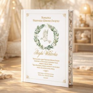 Elegancka książka pamiątkowa z ilustracją białego gołębia w zielonej koronie z roślin, tytuł "Bajki Wiktorka" napisany złotymi literami. W tle widoczna miękka, jasna dekoracja, sugerująca przytulne wnętrze.