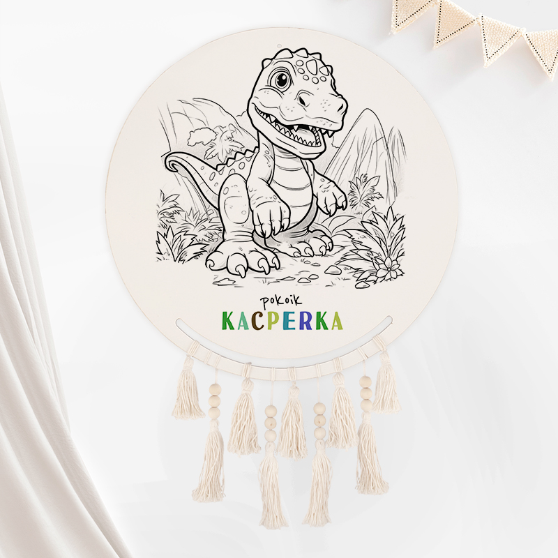 Okrągła dekoracja przedstawiająca dinozaura, z napisem "pokój Kacperka" w kolorowych literach, zawieszona na ścianie, z dekoracyjnymi frędzlami na dole.
