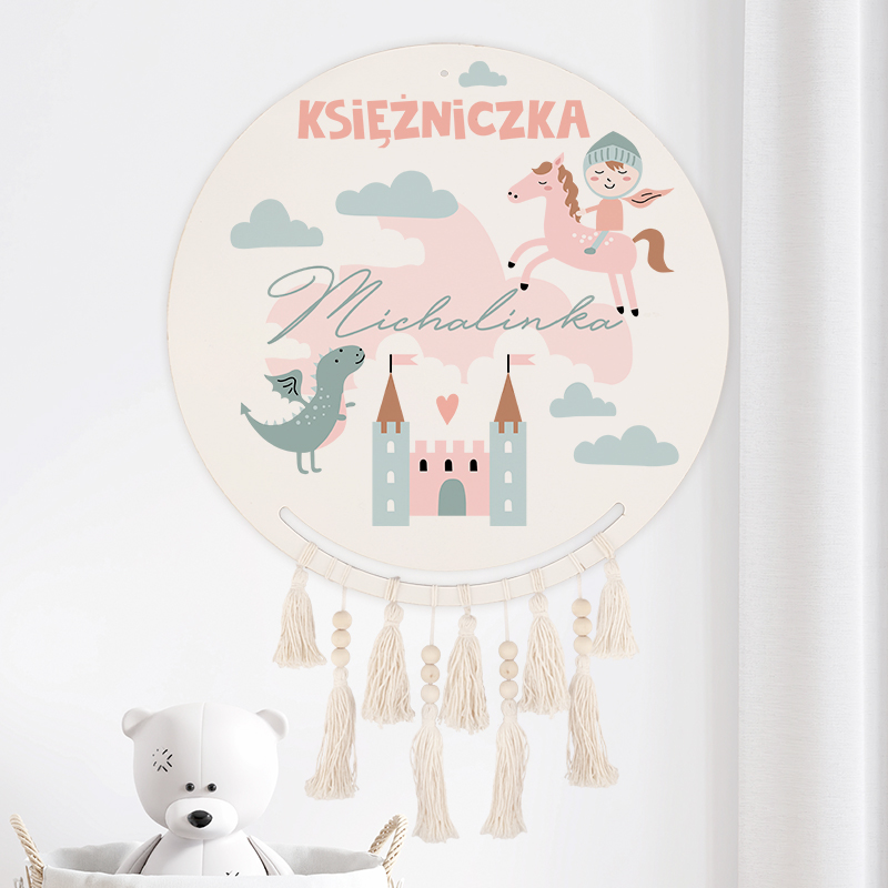 Okrągła dekoracja ścienna z napisem "Księżniczka Michałinka", przedstawiająca różowe konia, zielonego smoka, zamek i chmurki w pastelowych kolorach, z frędzlami u dołu.