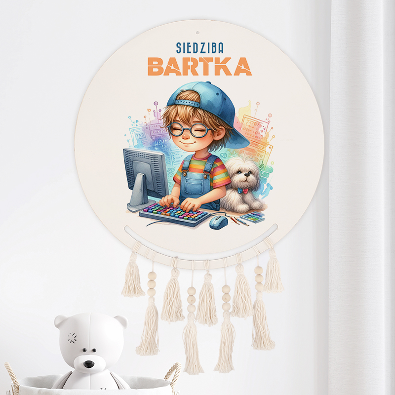 Ilustracja przedstawiająca chłopca w czapce i okularach, siedzącego przy komputerze z kolorową klawiaturą, obok niego mały piesek. Tło z cyfrowymi wzorami i napisem 'SIEDZIBA BARTKA'. W dolnej części wiszą frędzle.