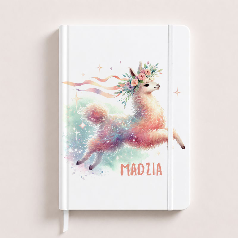Biały notes z ilustracją kolorowej lamy w kwiatowej koronie i napisem "MADZIA". Llama skacze wśród pastelowych kolorów i błyszczących elementów.