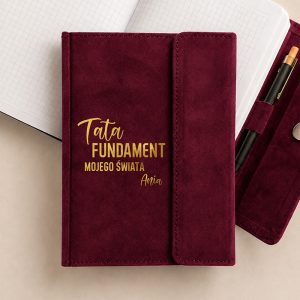 A bordowy notes z napisem "Tata FUNDAMENT mojego świata" i imieniem "Ania" na okładce.
