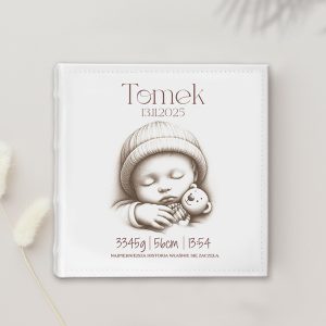 Okładka albumu o białym tle, przedstawiająca rysunek małego śpiącego niemowlęcia w wełnianej czapce trzymającego pluszowego misia. Na okładce widnieje imię 'Tomek' oraz daty 13.11.2025, waga 3345g, długość 56cm i czas 3:54, z napisem 'Najpiękniejsza historia właśnie się zaczęła.'