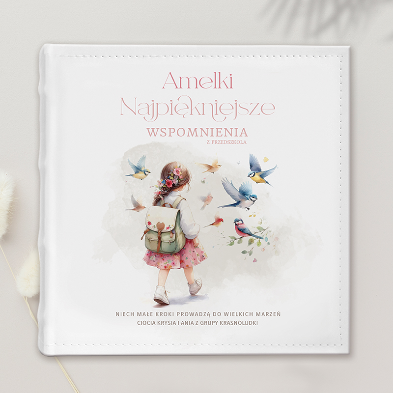 Okładka książki z tytułem 'Amelki Najpiękniejsze Wspomnienia z Przedszkola', przedstawiająca dziewczynkę z plecakiem, otoczoną ptakami i kwiatami, w pastelowych kolorach.