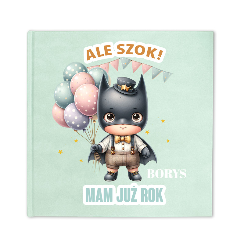 Ilustracja z małym chłopcem przebranym za superbohatera z balonami w kolorze pastelowym, z napisem 'ALE SZOK!' oraz 'MAM JUŻ ROK' na okładce książki.