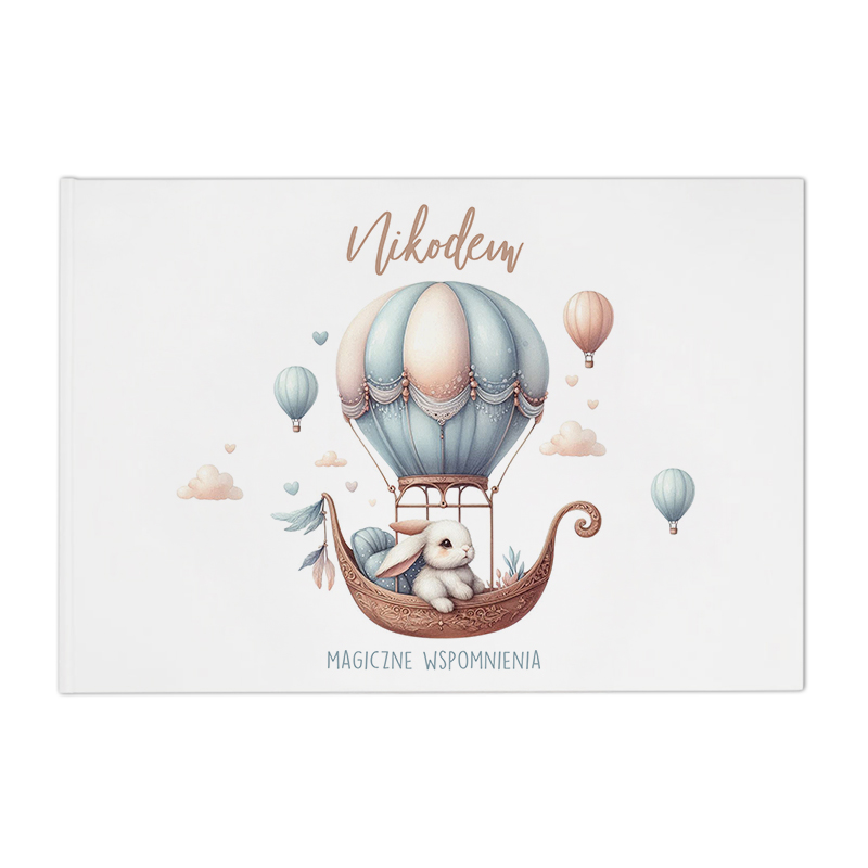 Ilustracja przedstawiająca balon na gorące powietrze unoszący się nad chmurkami, w którym siedzi królik. W tle widać balony w różnych kolorach. Na górze napis 'Nikodem' a poniżej 'MAGICZNE WSPOMNIENIA'.