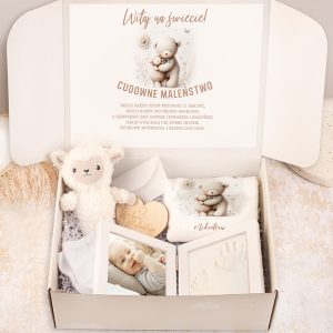 Otwarta paczka z prezentem z okazji narodzin, zawierająca pluszowe zwierzątko w kształcie owieczki, małe ubranko, ramki ze zdjęciem i odciskiem stóp dziecka, a także kartkę z powitaniem oraz życzeniami w pastelowych kolorach.
